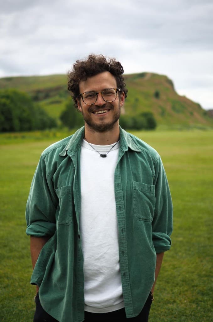 Anthony Guiducci smiling outdoors in a green field